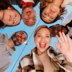 A diverse group of friends smiling into a camera outdoors, capturing a joyful moment.