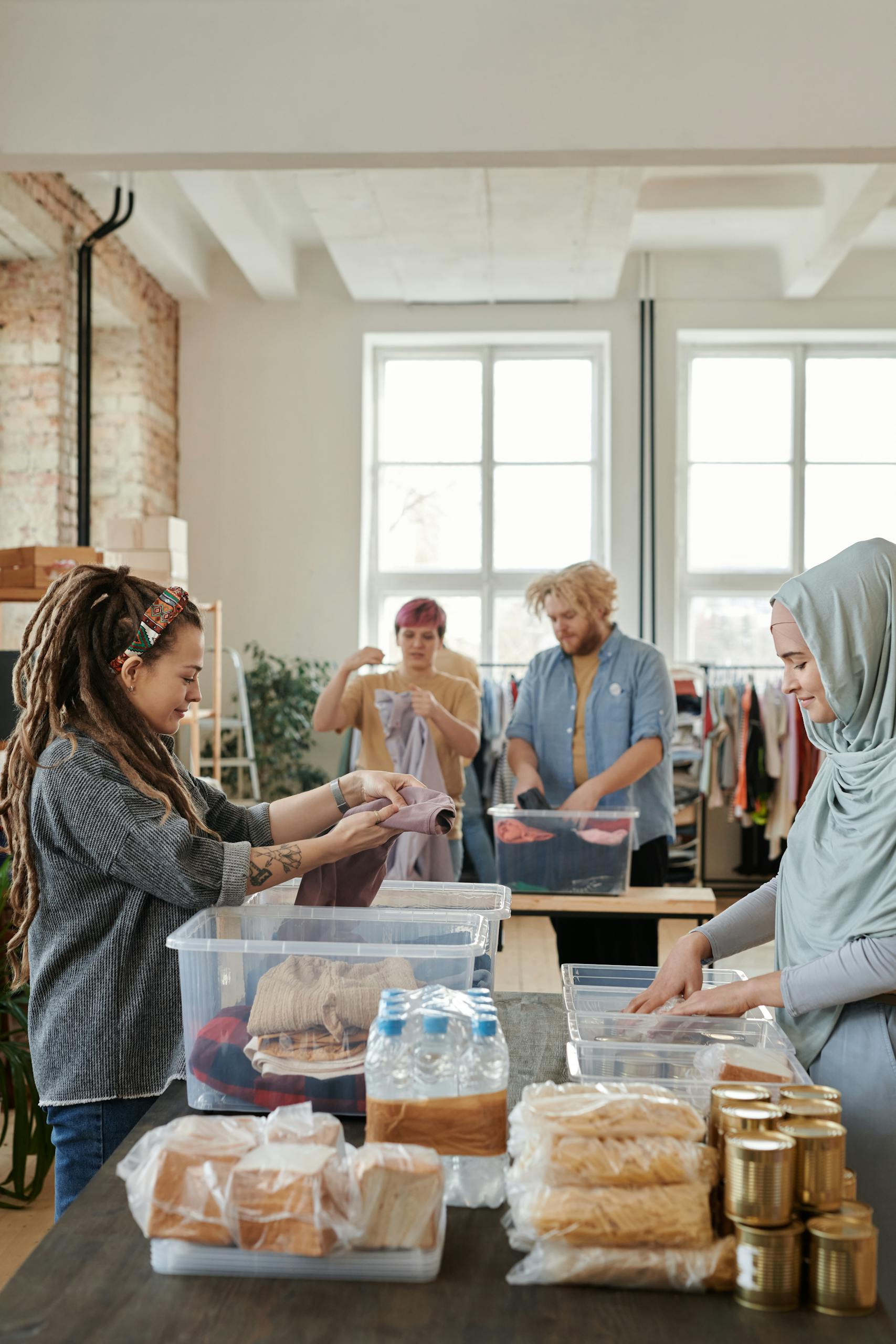A diverse group of volunteers sorting clothes and food items at an indoor donation center.
