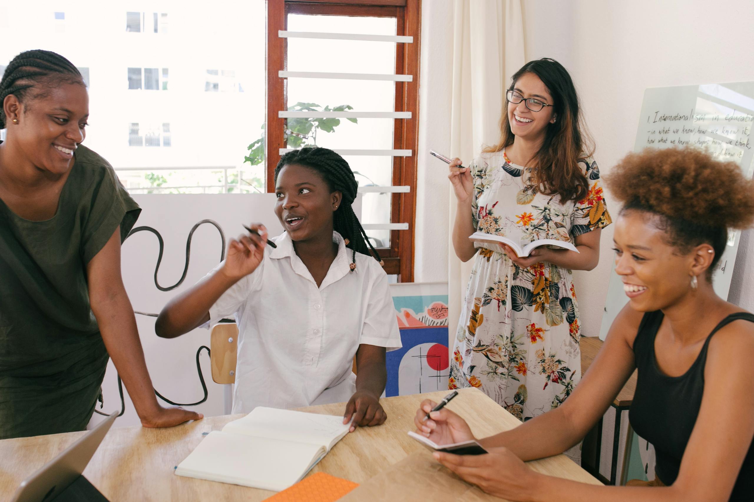A diverse group of women engaged in a lively office meeting, sharing ideas and brainstorming together.