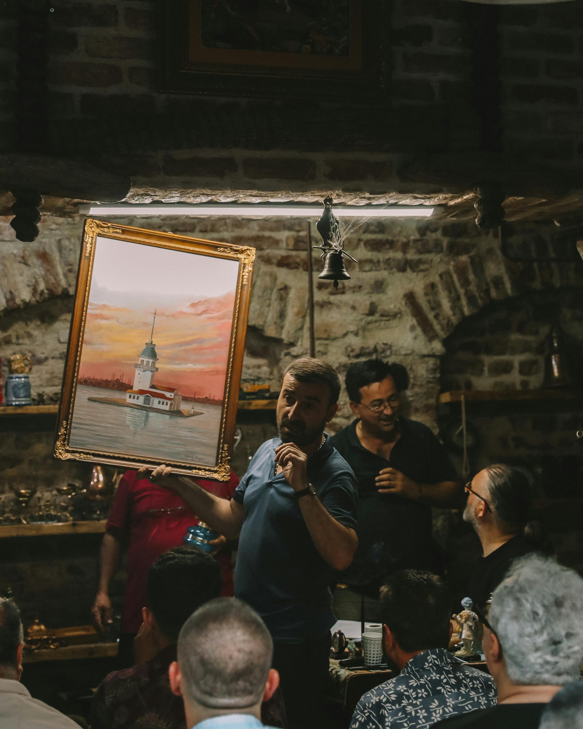 Art auction with painting of Istanbul's Maiden's Tower held in a historic indoor venue.